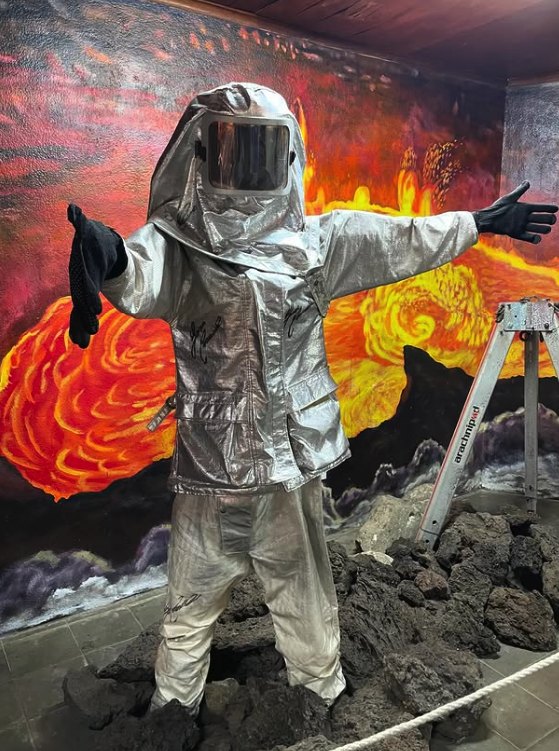 A silver heat suit displayed against a painted lava wall inside the Masaya Volcano park museum