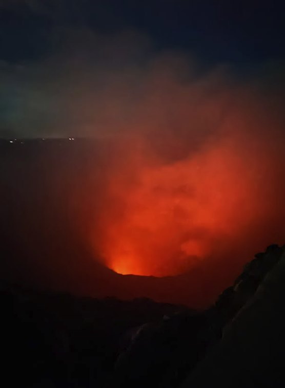 Orange light rising from the crater floor at Masaya Volcano late in the evening